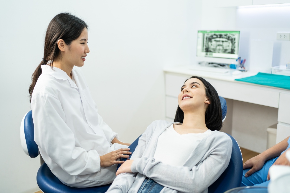 What to Do If You Have an Abscess Dentist in white coat consulting with patient in dental chair about tooth abscess treatment.