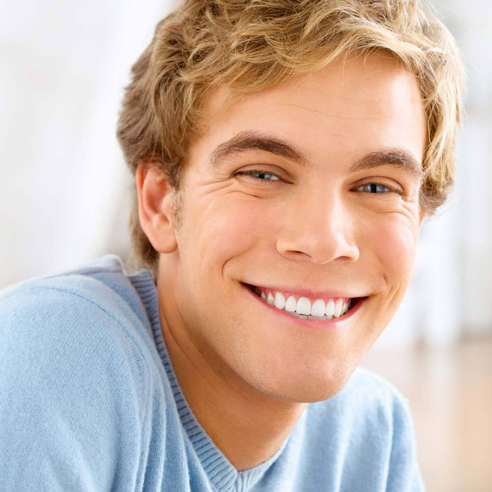 Portrait of Smiling Young Adult with Blonde Hair wearing a Blue T-Shirt after visiting One Eleven Dental Care