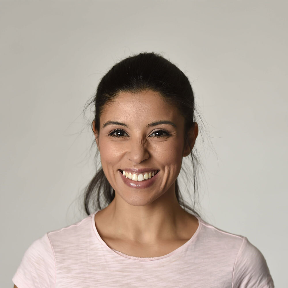 Portrait of a Smiling Hispanic Woman with a Grey Background after a Visit to One Eleven Dental Care