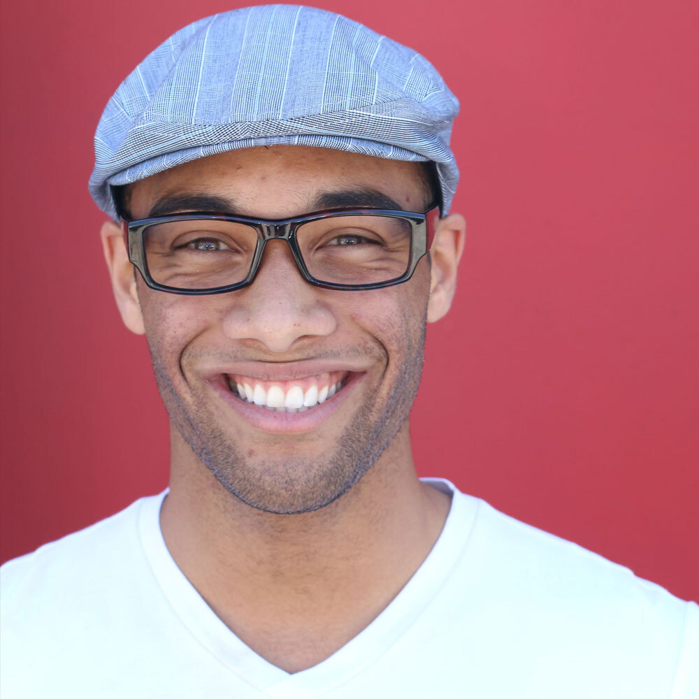 Portrait of African-American Man Smiling and Wearing a Blue Shirt with a Red Background after a visit to One Eleven Dental Care