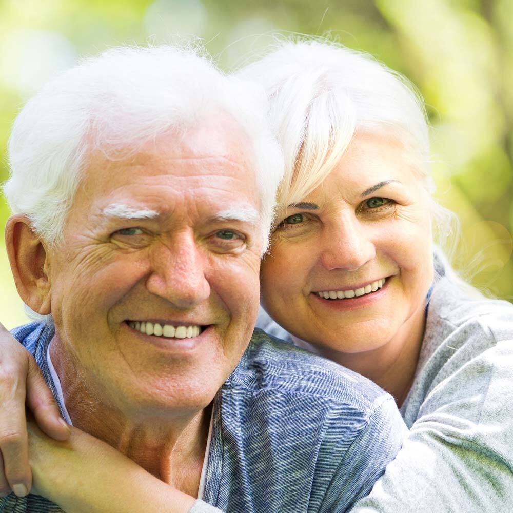 Portrait of Senior Couple in the Nature Hugging and Smiling after a Visit to One Eleven Dental Care