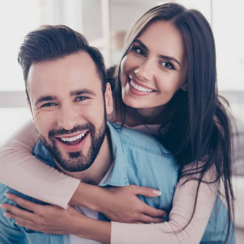 Portrait of Smiling Couple Hugging and Looking into the Camera after a Visit to One Eleven Dental Care