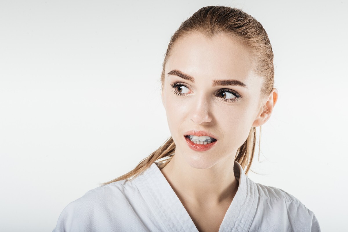 Protecting Your Teeth from Trauma During Sports Young woman in white dental coat with concerned expression about tooth injury.