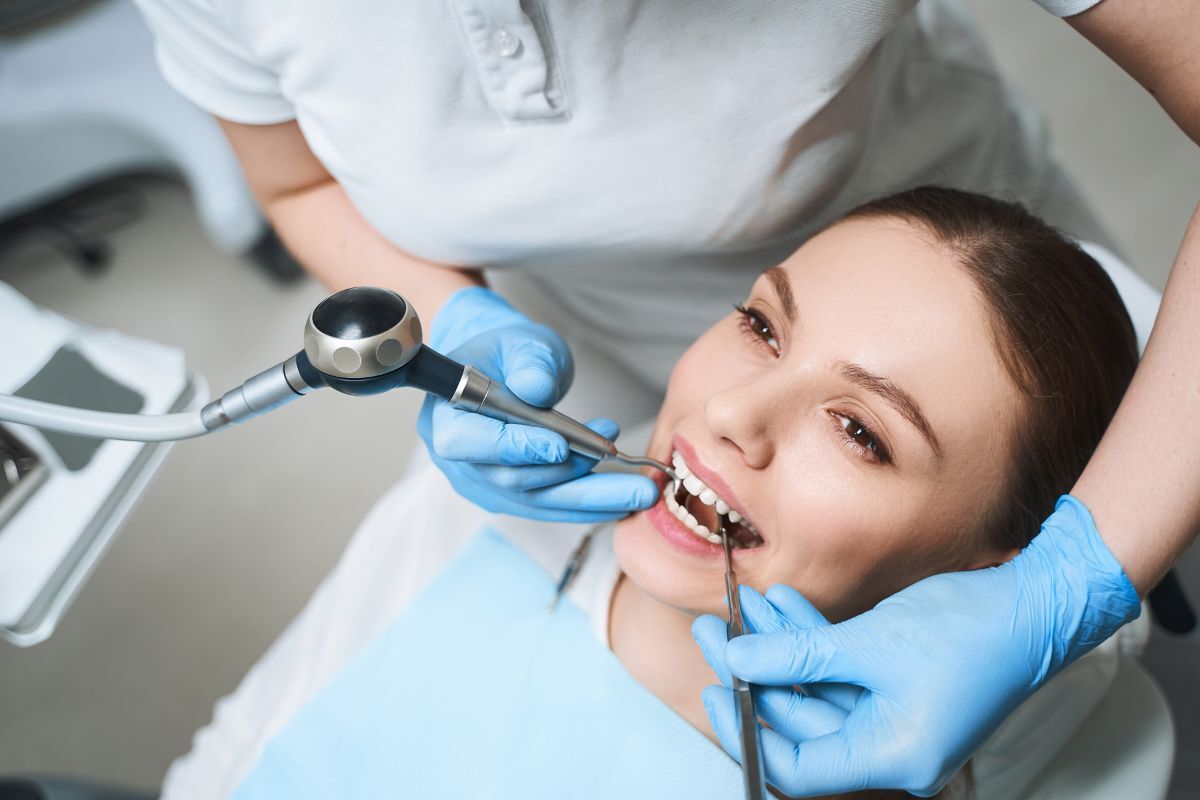 Dentist examining patient's teeth with dental tools during filling procedure.