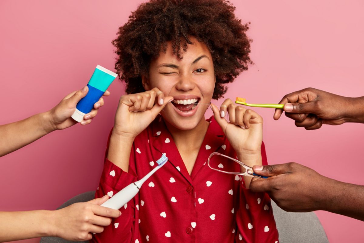 Best Dental Gadget Gifts Happy woman with red heart-patterned shirt surrounded by dental care products and tools.