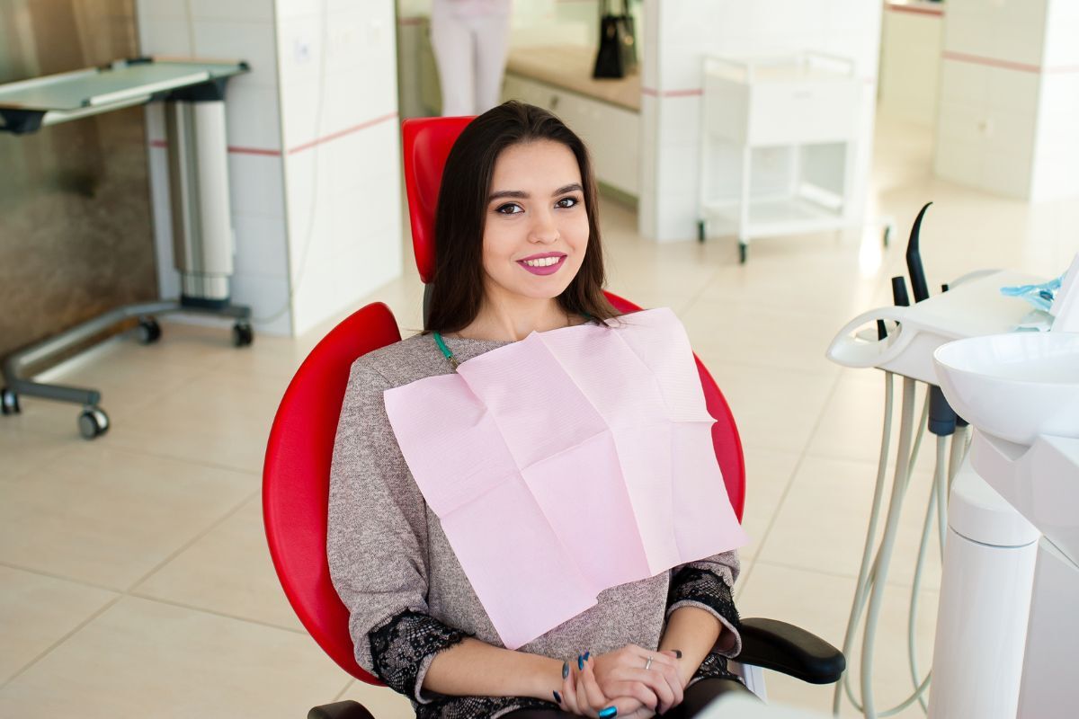 Smiling woman holding pink bib in dental chair at Bixby, OK practice.