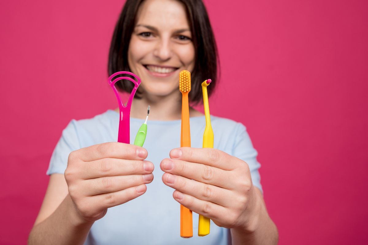 What Should Be in Your Dental Travel Kit Woman holding colorful dental care tools including toothbrushes and floss for travel kit.