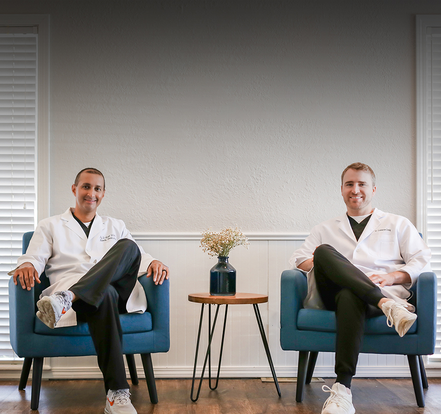 111 dental Two smiling dentists in white coats sitting in modern chairs at Bixby dental practice.