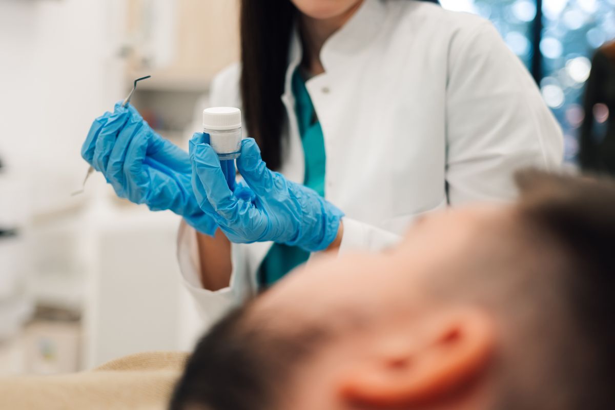 Can dental fillings be whitened Healthcare professional holding medication bottle with blue gloves during dental examination.