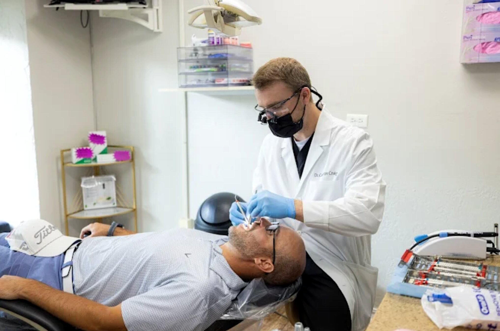 Dentist in blue gloves examines patient's teeth during dental treatment in Bixby office.